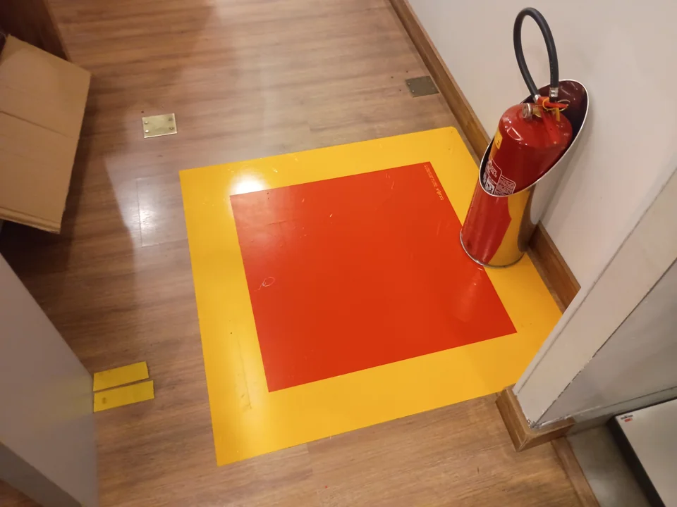 Extintor vermelho próximo a demarcação vermelha e amarela no piso